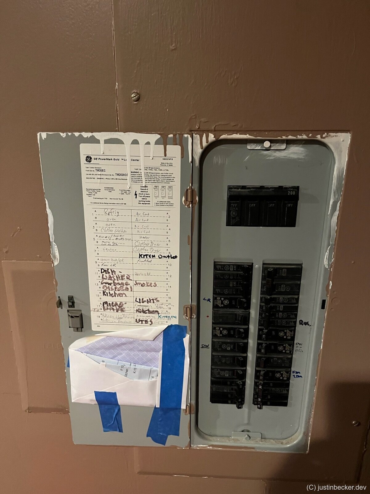 An open electrical breaker panel with a handwritten circuit directory listing which breaker feeds each room